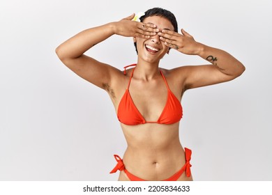 Young Hispanic Woman With Short Hair Wearing Bikini Covering Eyes With Hands Smiling Cheerful And Funny. Blind Concept. 