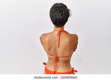 Young Hispanic Woman With Short Hair Wearing Bikini Standing Backwards Looking Away With Crossed Arms 