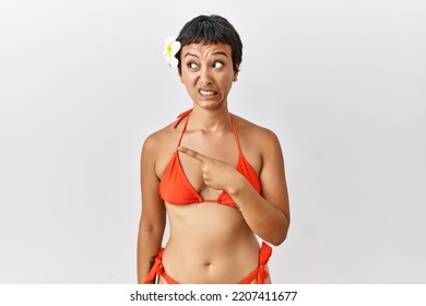 Young Hispanic Woman With Short Hair Wearing Bikini Pointing Aside Worried And Nervous With Forefinger, Concerned And Surprised Expression 