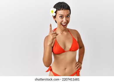 Young Hispanic Woman With Short Hair Wearing Bikini Pointing Finger Up With Successful Idea. Exited And Happy. Number One. 