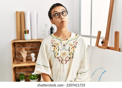 Young Hispanic Woman With Short Hair At Art Studio Making Fish Face With Lips, Crazy And Comical Gesture. Funny Expression. 