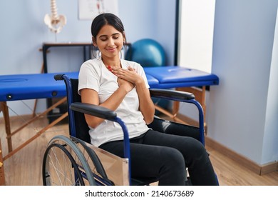 Young Hispanic Woman Sitting On Wheelchair At Physiotherapy Clinic Smiling With Hands On Chest, Eyes Closed With Grateful Gesture On Face. Health Concept. 