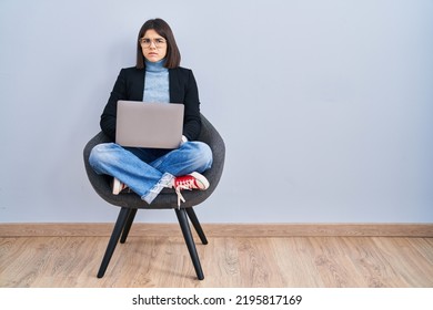 Young Hispanic Woman Sitting On Chair Using Computer Laptop Skeptic And Nervous, Frowning Upset Because Of Problem. Negative Person. 