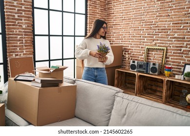 Young Hispanic Woman Smiling Confident Holding Lavander Plant At New Home
