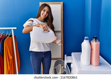 Young Hispanic Woman Smiling Confident Pouring Detergent At Laundry Room