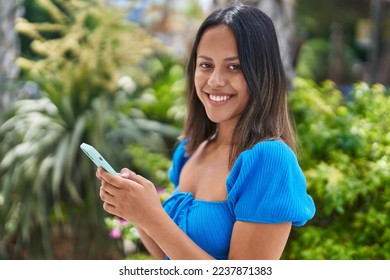 Young hispanic woman smiling confident using smartphone at park - Powered by Shutterstock