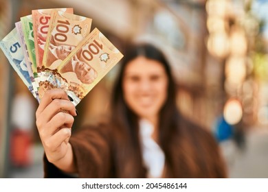 Young Hispanic Woman Smiling Happy Holding Canadian Dollars At The City.