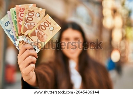 Young hispanic woman smiling happy holding canadian dollars at the city. Foto d'archivio © 