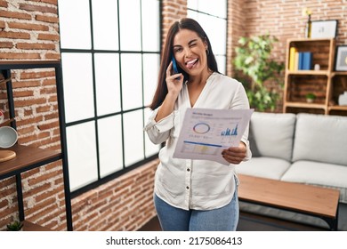 Young Hispanic Woman Speaking On The Phone About Bills Sticking Tongue Out Happy With Funny Expression. 