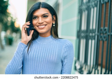 Young Hispanic Woman Speaking On The Phone At The Town