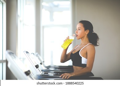 Young Hispanic Woman In Sportswear Running On Treadmill At Gym And Drinking Water. Healthy Lifestyle And Sport Concepts.