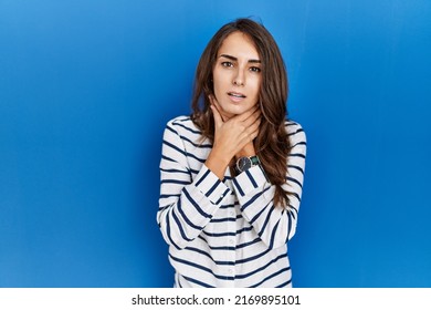 Young hispanic woman standing over blue isolated background shouting suffocate because painful strangle. health problem. asphyxiate and suicide concept. 