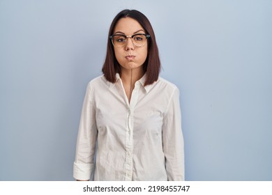 Young Hispanic Woman Standing Over White Background Puffing Cheeks With Funny Face. Mouth Inflated With Air, Crazy Expression. 