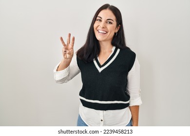 Young hispanic woman standing over isolated background showing and pointing up with fingers number three while smiling confident and happy. 
