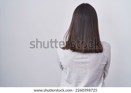 Young hispanic woman standing over white background standing backwards looking away with crossed arms 