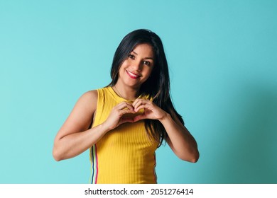 Young Hispanic Woman With Straight Hair And Smiling In Love Doing Heart Symbol Shape With Hands.