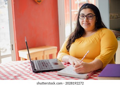 Young hispanic woman studying from home - happy woman working from home- homework or homeschool - Powered by Shutterstock