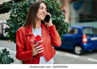 Young hispanic woman talking on the smartphone and drinking coffee at the city. - Powered by Shutterstock