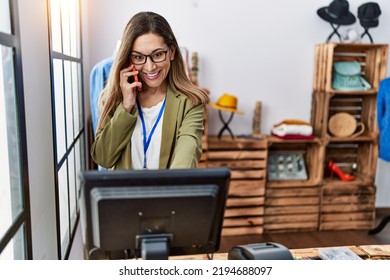 Young Hispanic Woman Talking On The Smartphone Working At Clothing Store