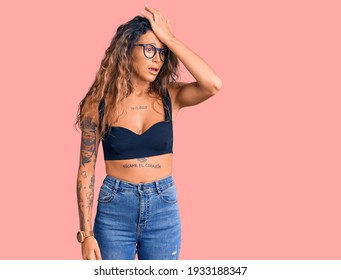 Young Hispanic Woman With Tattoo Wearing Casual Clothes And Glasses Surprised With Hand On Head For Mistake, Remember Error. Forgot, Bad Memory Concept. 