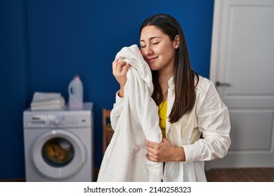 Young Hispanic Woman Touching Face With Soft Towel At Laundry Room