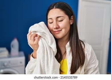 Young Hispanic Woman Touching Face With Soft Towel At Laundry Room