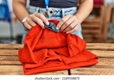 Young Hispanic Woman Touching Security Alarm Clothes At Clothing Store