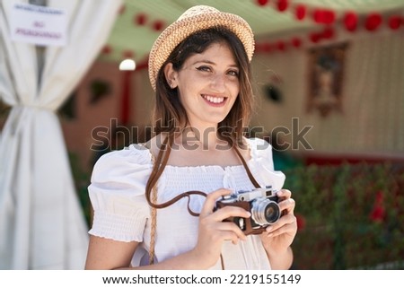 Young hispanic woman tourist smiling confident using camera at restaurant