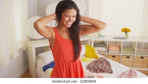 Young Hispanic Woman Trying On Clothes In Bedroom