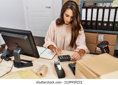 Young Hispanic Woman Using Calculator At Storehouse