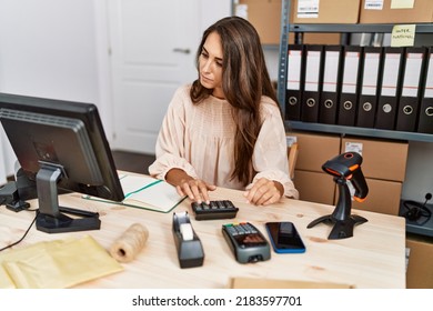 Young Hispanic Woman Using Calculator At Storehouse