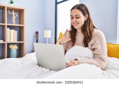 Young Hispanic Woman Using Computer Laptop On The Bed Smiling Happy Pointing With Hand And Finger 