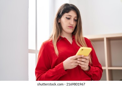 Young Hispanic Woman Using Smartphone With Serious Expression At Home