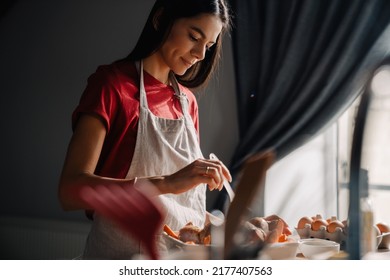 Young hispanic woman using tablet-computer while cooking in kitchen at home