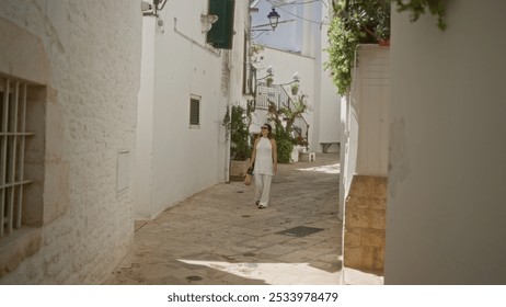 Young hispanic woman walking through the charming white streets of the old town in locorotondo, puglia, italy, surrounded by traditional architecture. - Powered by Shutterstock