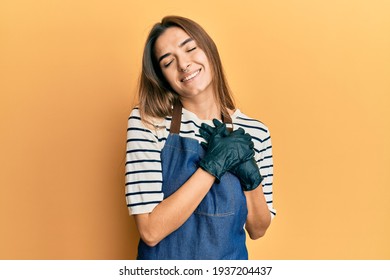 Young hispanic woman wearing barber apron smiling with hands on chest with closed eyes and grateful gesture on face. health concept.  - Powered by Shutterstock