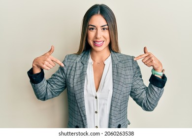 Young hispanic woman wearing business clothes looking confident with smile on face, pointing oneself with fingers proud and happy. 