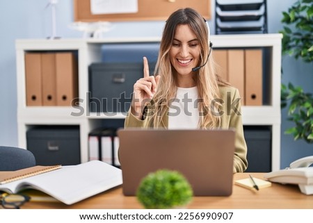 Young hispanic woman wearing call center agent headset working at the office surprised with an idea or question pointing finger with happy face, number one 