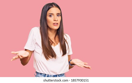 Young Hispanic Woman Wearing Casual White Tshirt Clueless And Confused With Open Arms, No Idea Concept. 