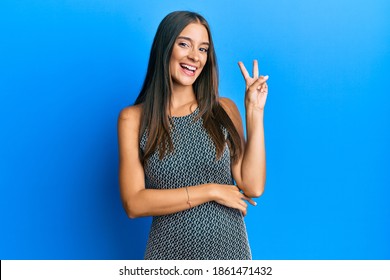 Young hispanic woman wearing casual clothes smiling with happy face winking at the camera doing victory sign. number two.  - Shutterstock ID 1861471432