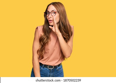 Young hispanic woman wearing casual clothes and glasses hand on mouth telling secret rumor, whispering malicious talk conversation 
