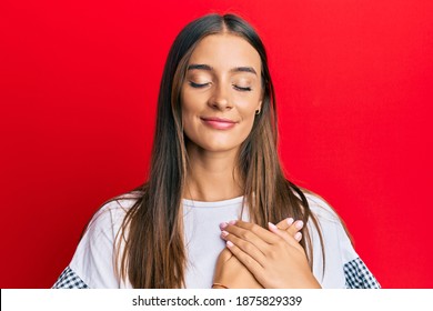 Young Hispanic Woman Wearing Casual Clothes Smiling With Hands On Chest With Closed Eyes And Grateful Gesture On Face. Health Concept. 