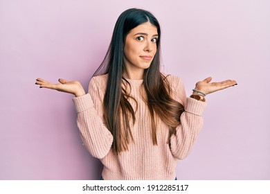Young hispanic woman wearing casual clothes clueless and confused with open arms, no idea and doubtful face.  - Shutterstock ID 1912285117