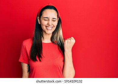 Young Hispanic Woman Wearing Casual Red T Shirt Celebrating Surprised And Amazed For Success With Arms Raised And Eyes Closed 