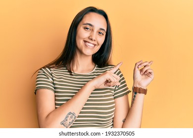 Young Hispanic Woman Wearing Casual Striped T Shirt Smiling And Looking At The Camera Pointing With Two Hands And Fingers To The Side. 