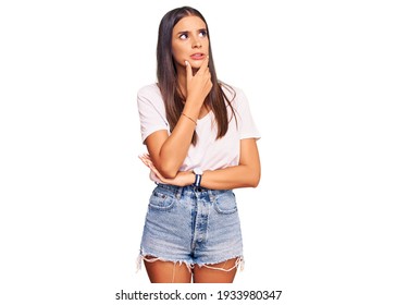 Young Hispanic Woman Wearing Casual White Tshirt Thinking Worried About A Question, Concerned And Nervous With Hand On Chin 