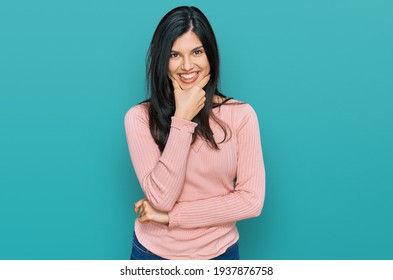 Young hispanic woman wearing casual clothes looking confident at the camera smiling with crossed arms and hand raised on chin. thinking positive. 