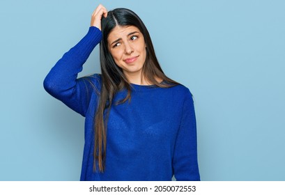 Young hispanic woman wearing casual clothes confuse and wonder about question. uncertain with doubt, thinking with hand on head. pensive concept.  - Shutterstock ID 2050072553