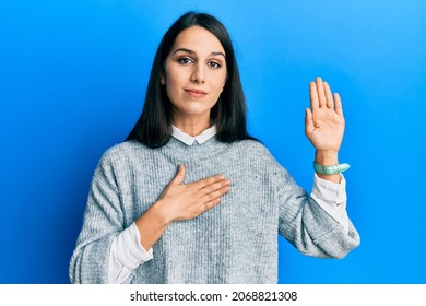 Young Hispanic Woman Wearing Casual Clothes Swearing With Hand On Chest And Open Palm, Making A Loyalty Promise Oath 