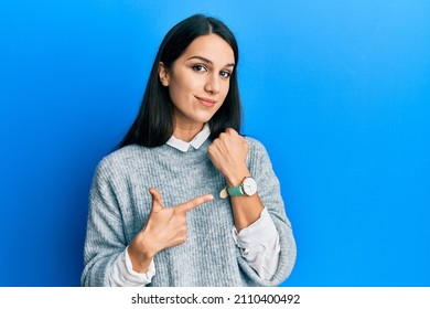 Young Hispanic Woman Wearing Casual Clothes In Hurry Pointing To Watch Time, Impatience, Looking At The Camera With Relaxed Expression 